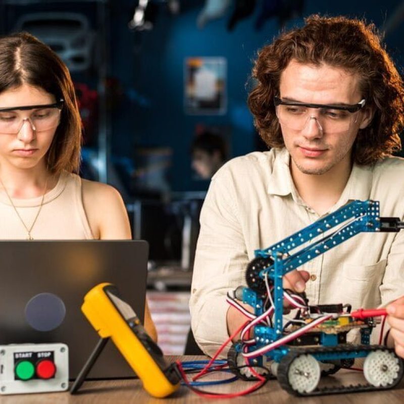 young-man-woman-protective-glasses-doing-experiments-robotics-laboratory_1268-23382